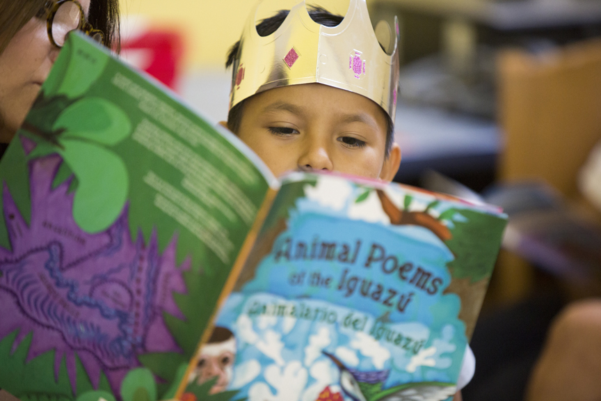 Child wearing golden crown while reading a book