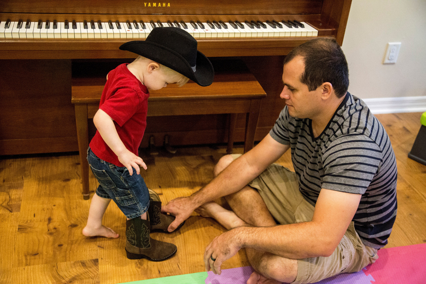 Father helping young boy put on boots