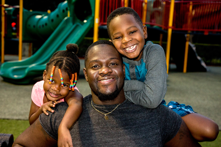 Father and two young children hugging in the park