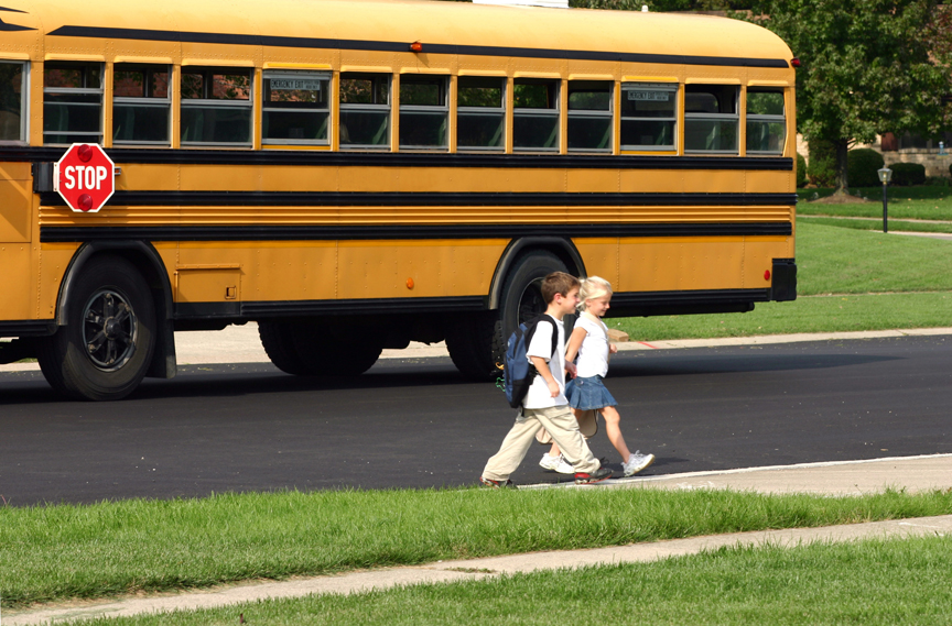 Children walking with school bus in background