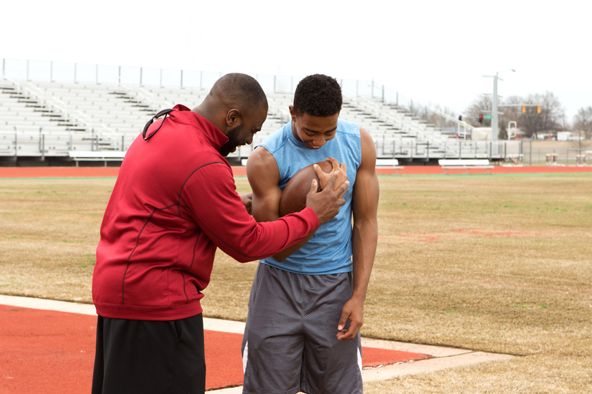 Coach and player holding football