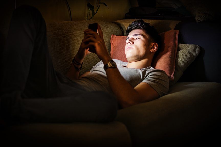 Teenager looking at phone in a dark room