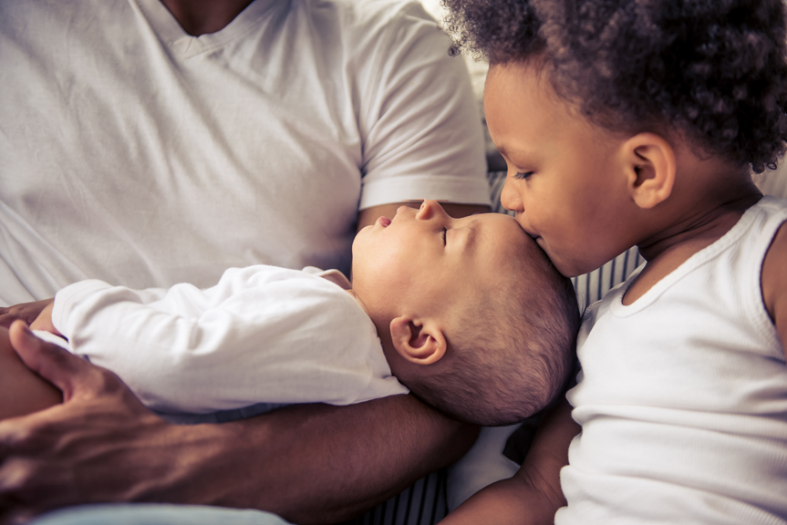 iStock-598072770 Girl kissing forehead of baby