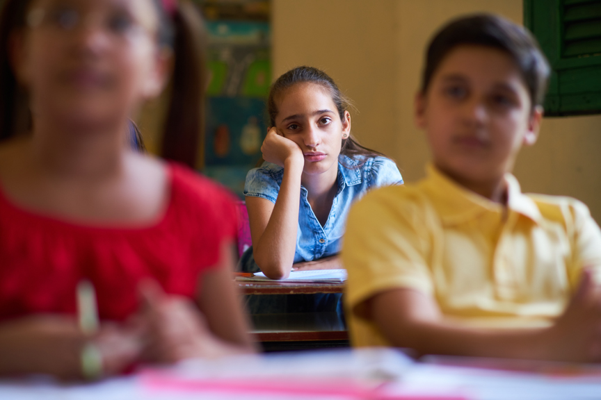Girl in classroom appearing bored or frustrated