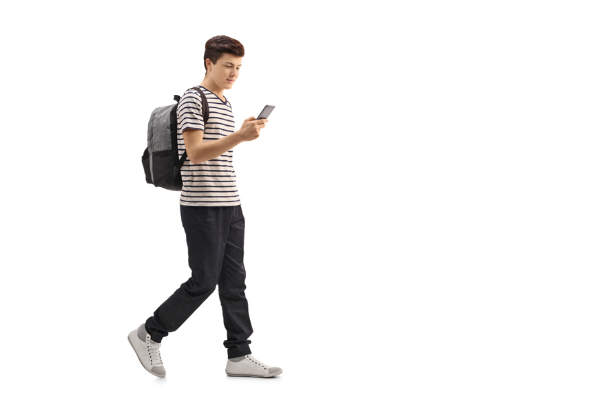 Teen boy walking while texting