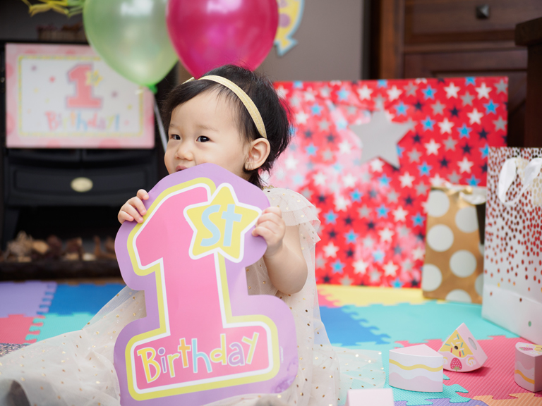 Young girl holding first birthday sign