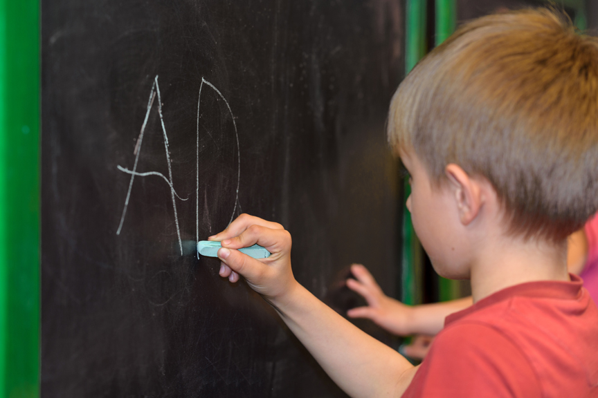 Children drawing letters on chalkboard