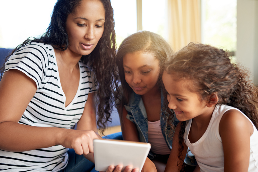 Woman sharing tablet with young girls