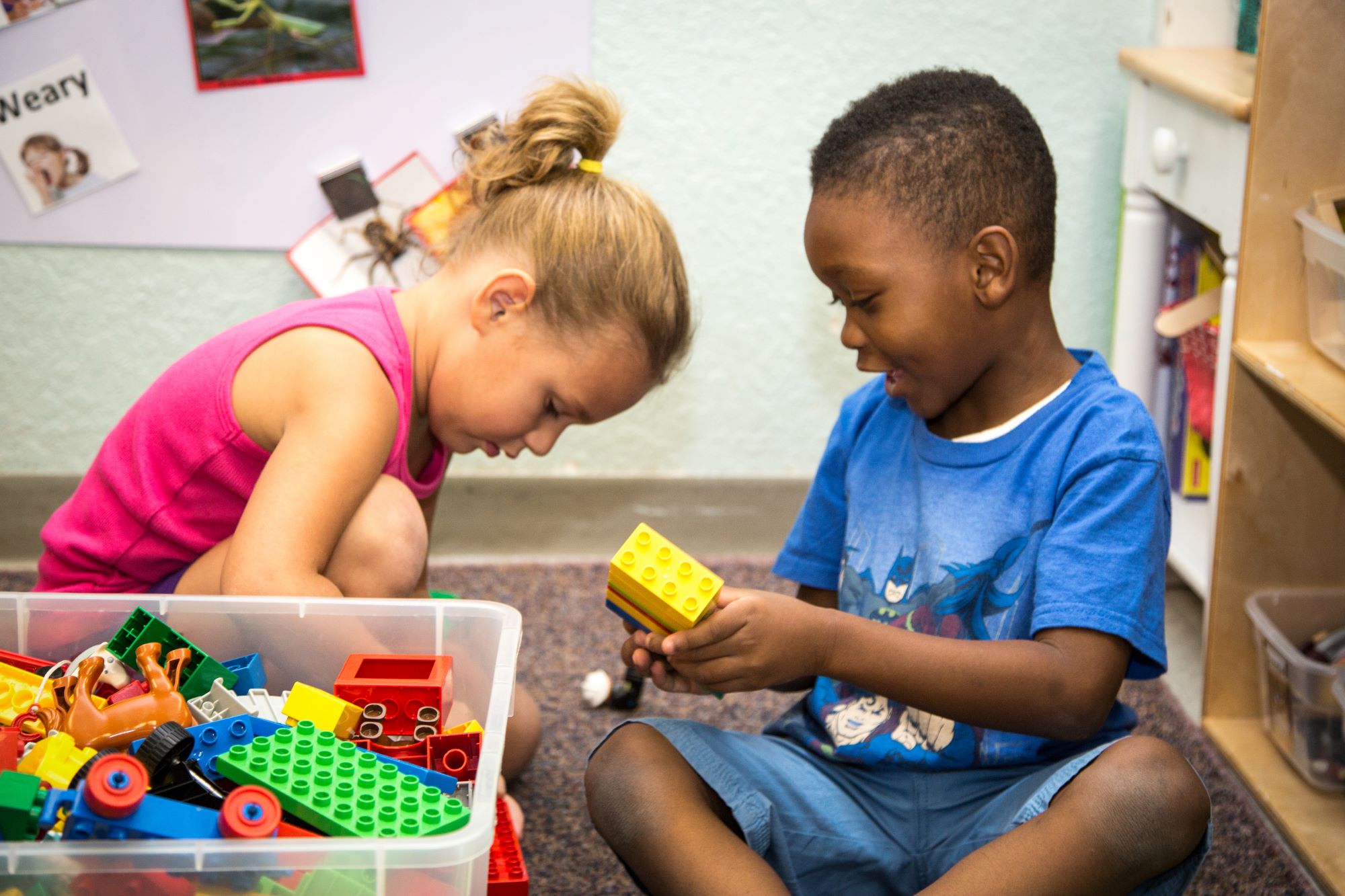 A girl and a boy playing with Legos together in a child care setting.
