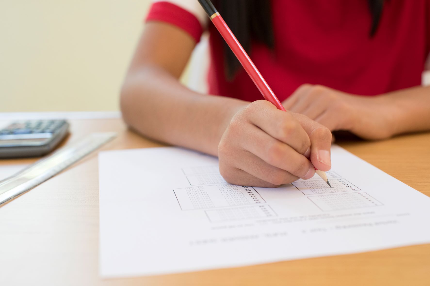 A young student holding a pencil filling in a test.