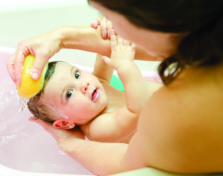 Baby in tub with mom washing him