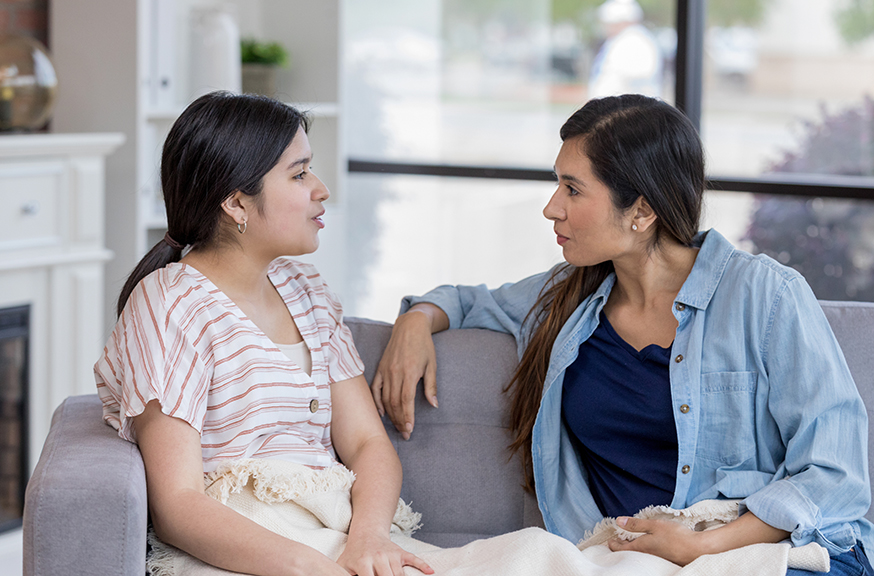 Mother and daughter talking on couch Mother and daughter talking on couch
