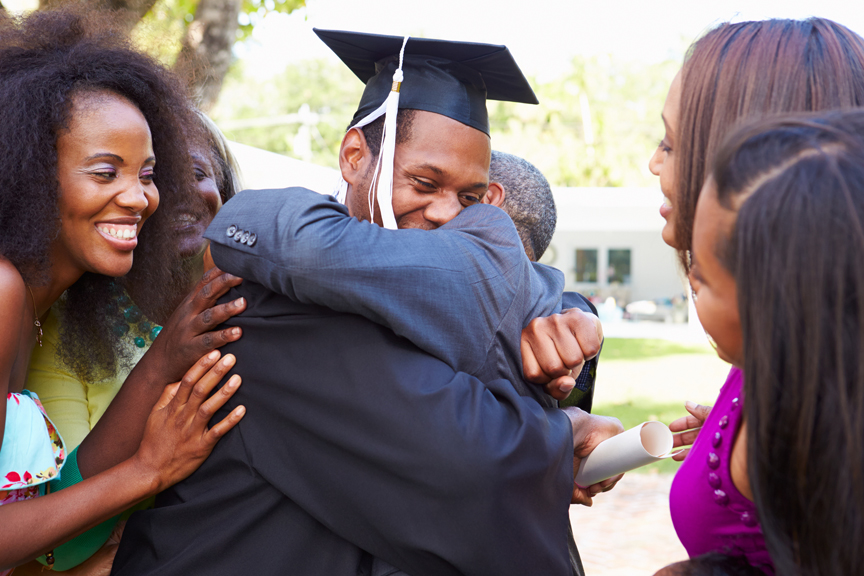 Student graduating and receiving hugs from friends and family