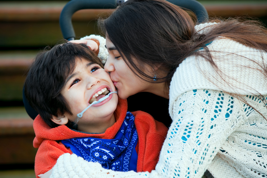 Mother kissing son in wheelchair