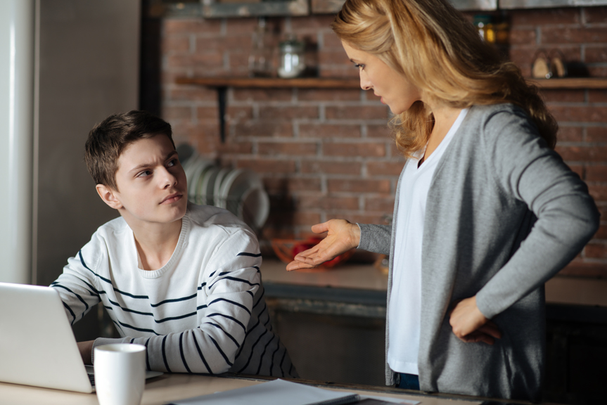 Woman having serious conversation with teen at a computer