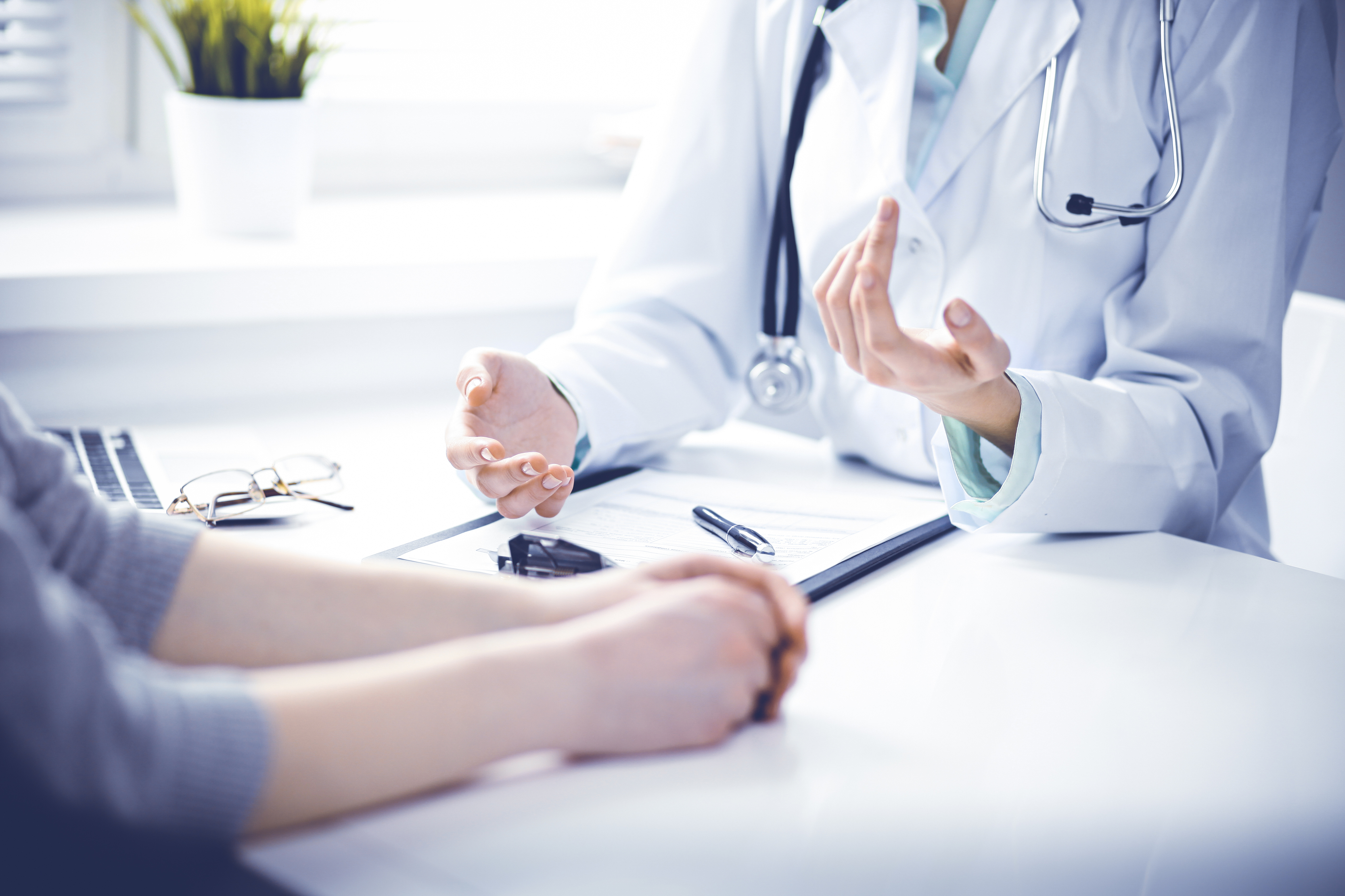 Woman at a table talking to her medical professional who's filling out a chart