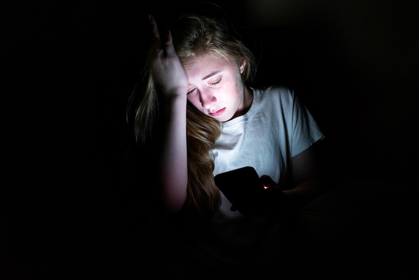 Teenager girl looking at phone in the dark.