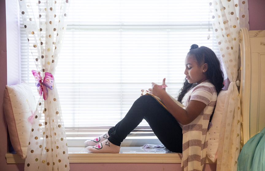 Girl reading in window sill.