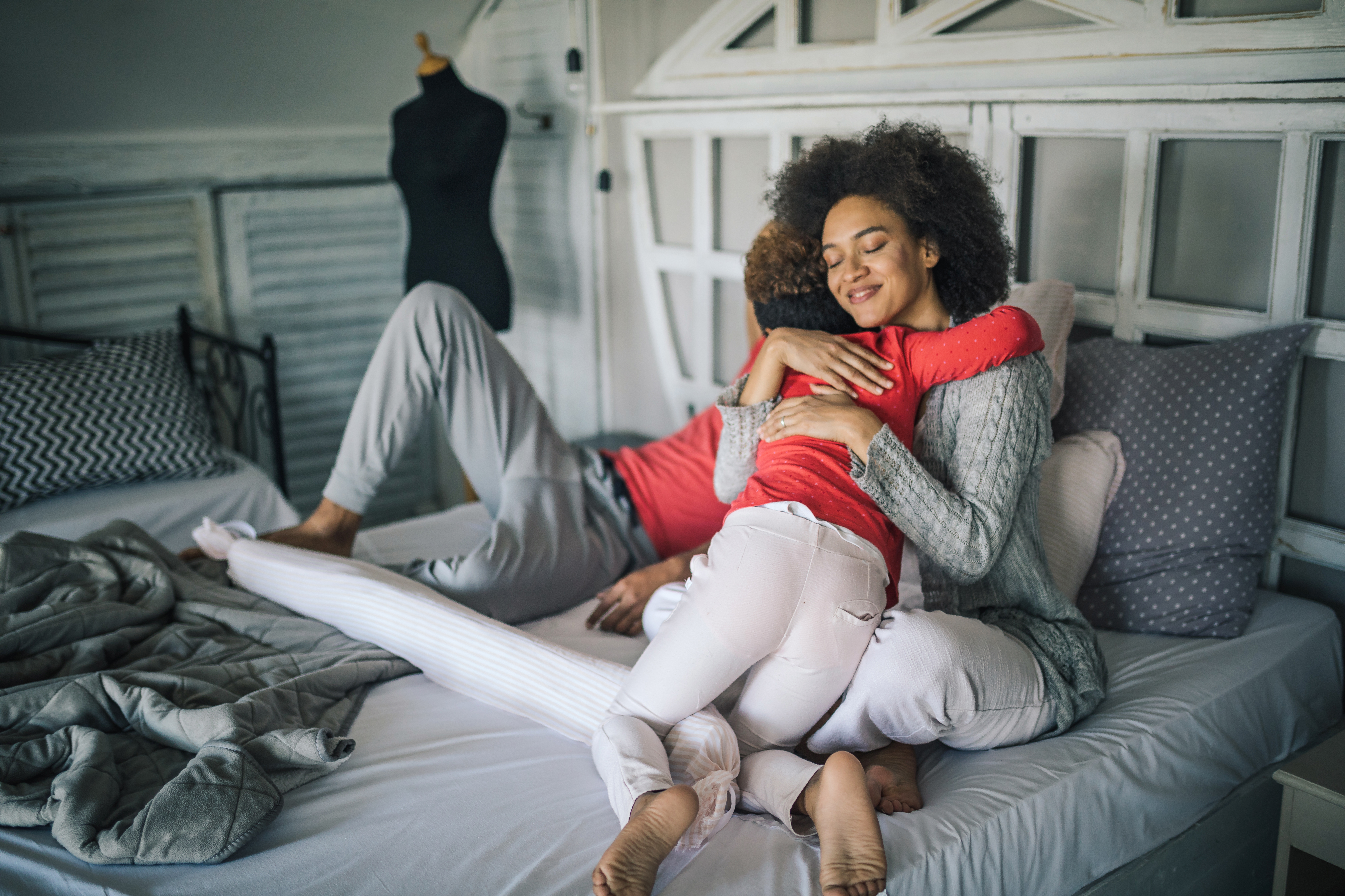 mother hugging child on bed, looking grateful