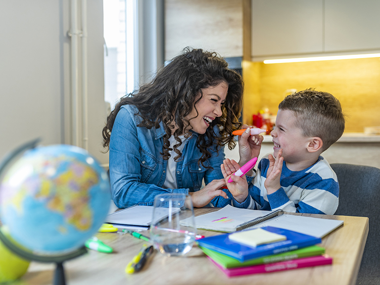 Mother and young son sitting at a kitchen table, drawing and giggling together